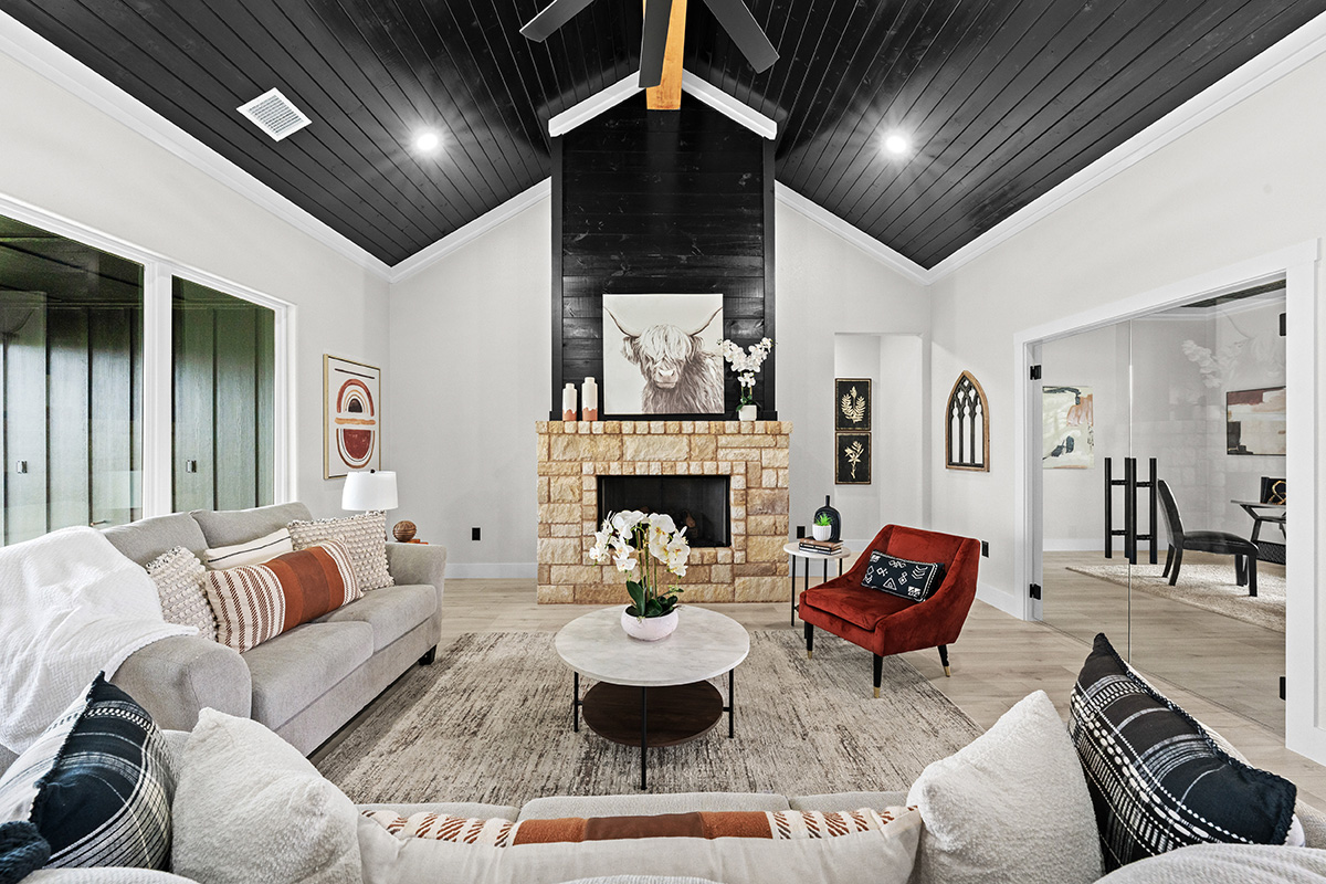 Living room with black shiplap vaulted ceiling and stone fireplace