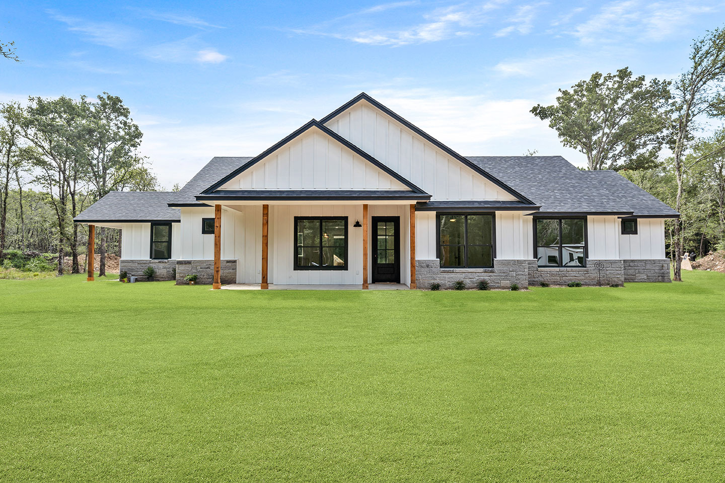 White farmhouse with cedar porch posts framed by oak trees