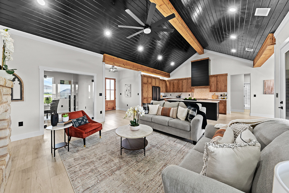 Open great room and kitchen under a cathedral shiplap ceiling with wood beams
