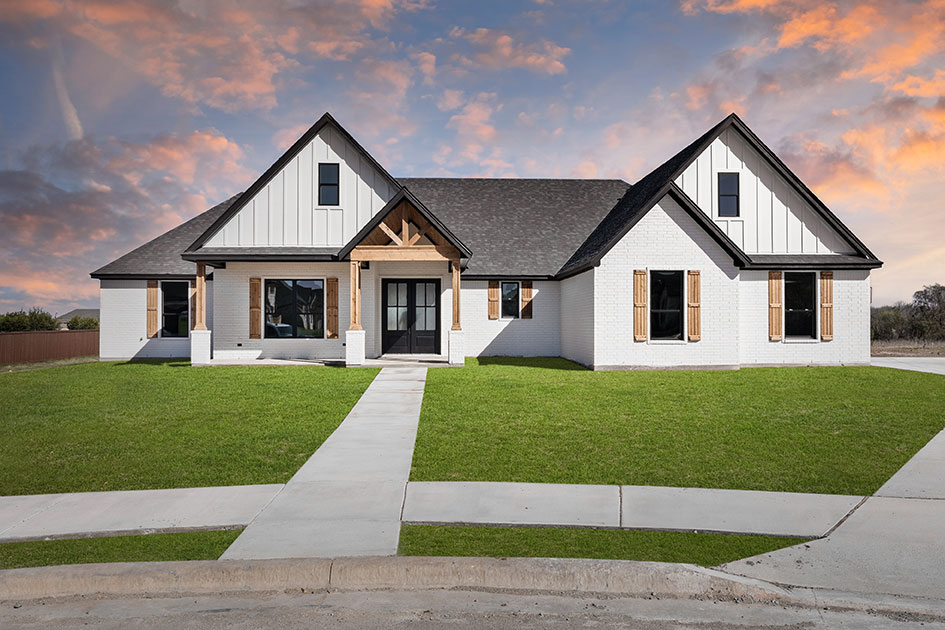 White painted brick farmhouse with cedar shutters at sunset