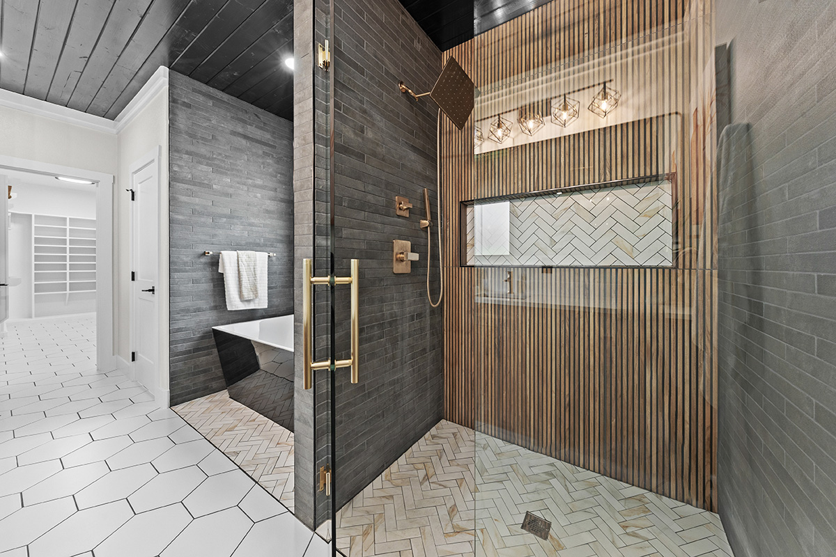 Walk-in shower with brass fixtures and herringbone tile