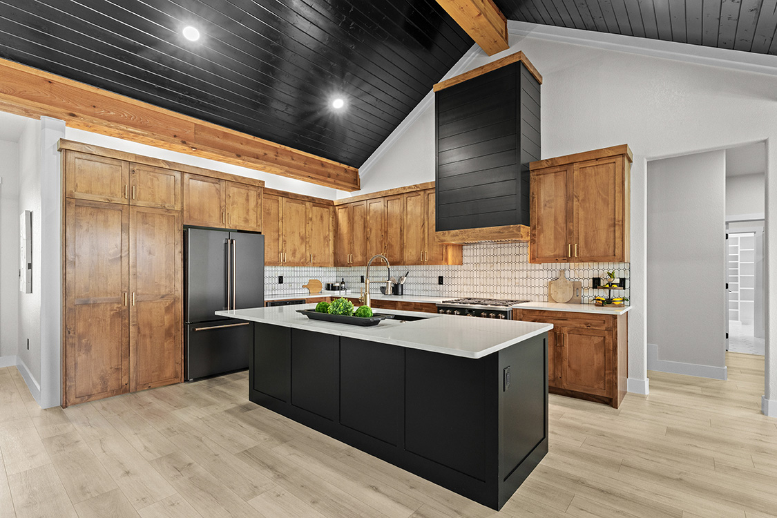 Kitchen with knotty alder cabinetry, black island and quartz counters